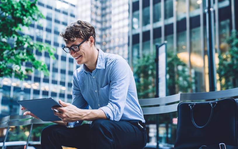 man-sits-on-bench-and-looks-at-tablet